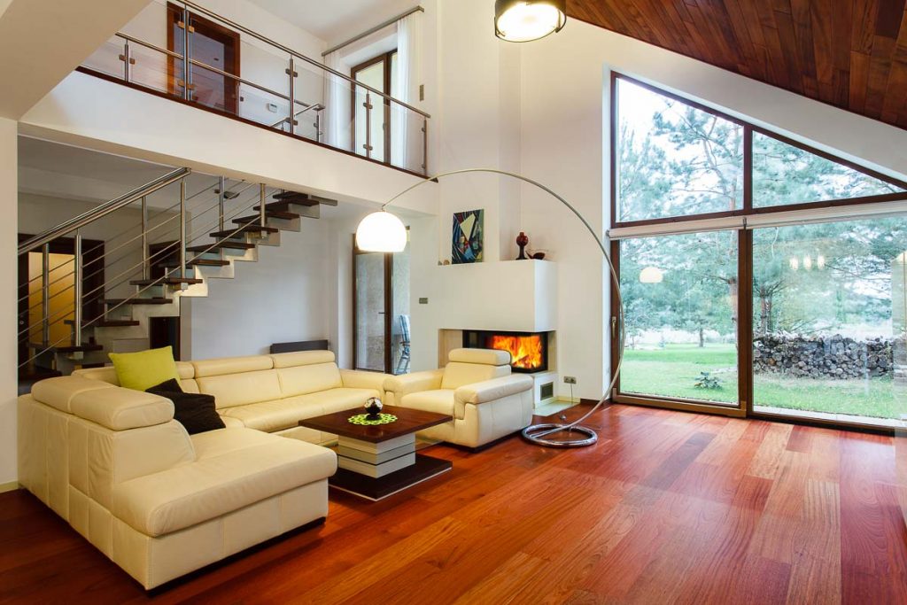 Foto de uma sala de estar em uma casa de dois andares com janelão para o jardim. 