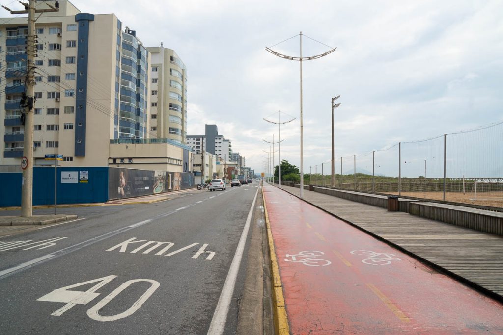 Foto da Avenida beira mar de Navegantes com a estrada asfaltada e com calçadas e ciclovias devidamente marcadas. 