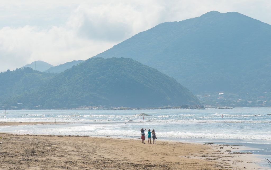 Foto da praia de Navegantes com pessoas caminhando na areia. 